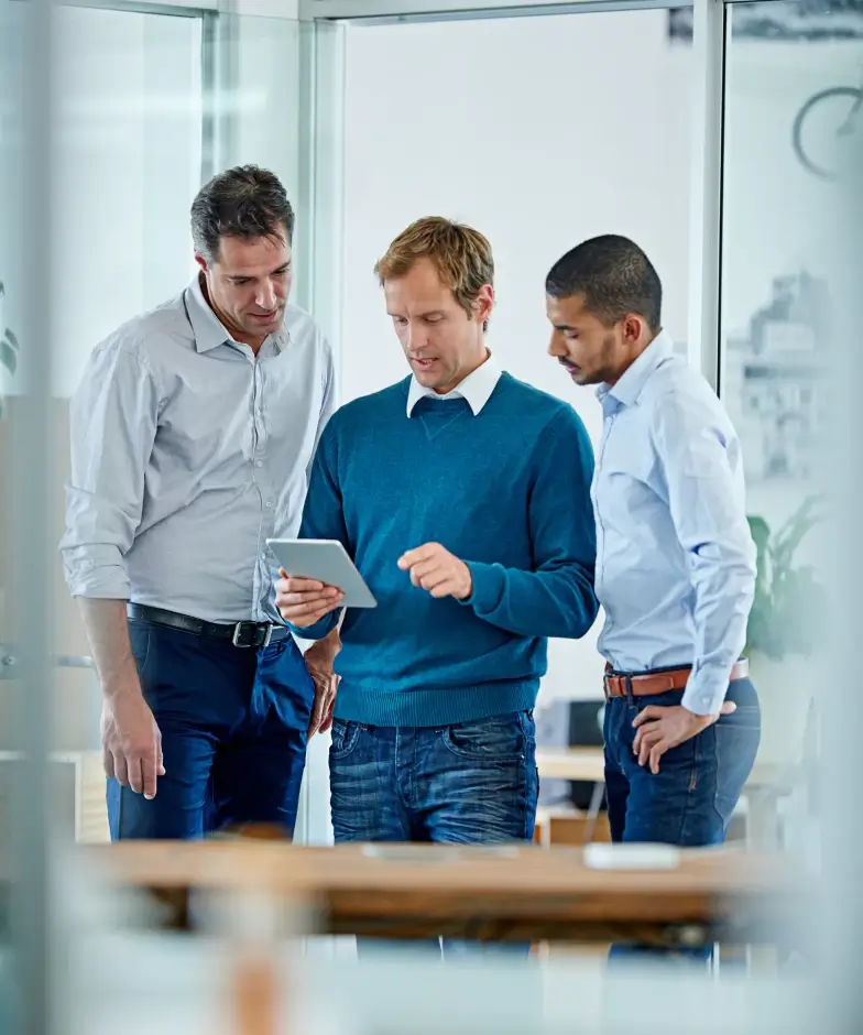 Three men looking at information on a tablet. Learn more about Stifel Venture Banking innovation community.