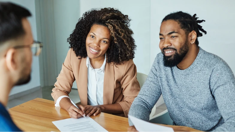 A joyful man and woman filling out an application. Login to handle any loans in process.