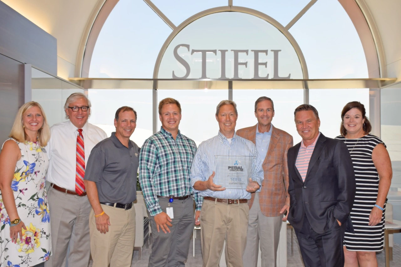 Stifel Leadership holding a plaque from Pedal the Cause, a race to raise money for cancer research.