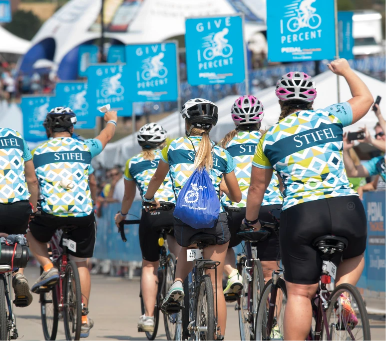 Stifel Pedal the Cause: Bikers cheering and crossing the finish line in Stifel Jerseys while riding their bikes.