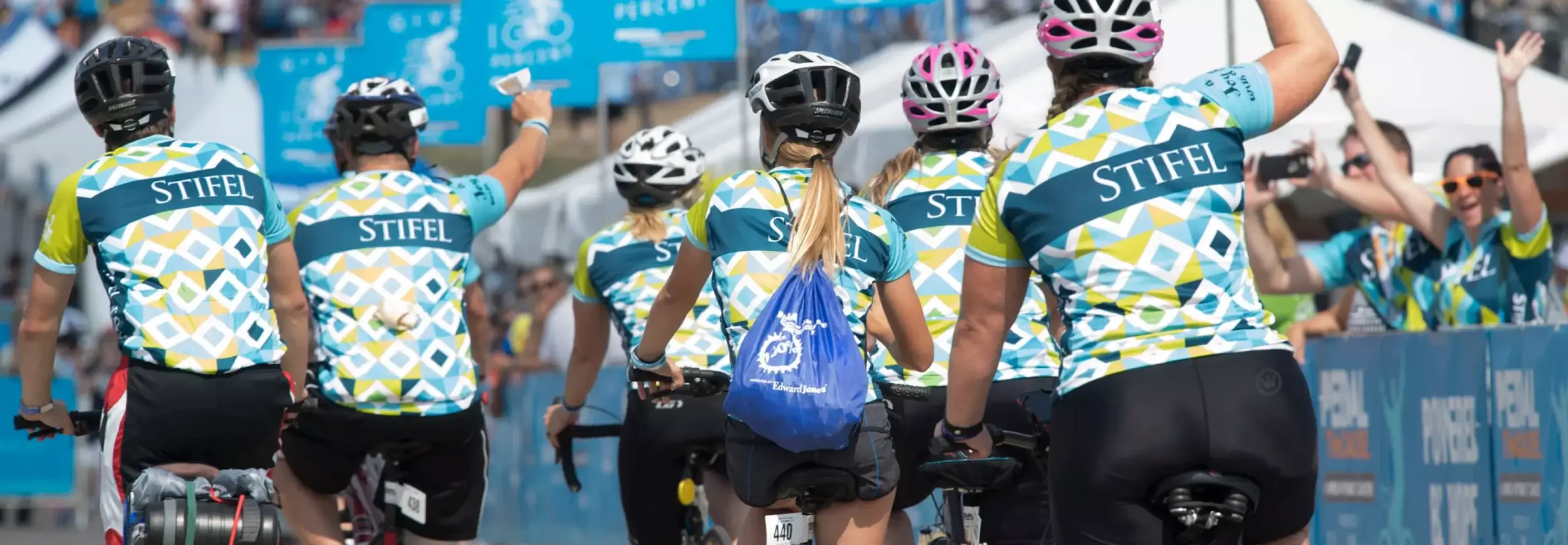 Pedal the Cause. Bikers celebrating and crossing the finish line wearing Stifel Jerseys.