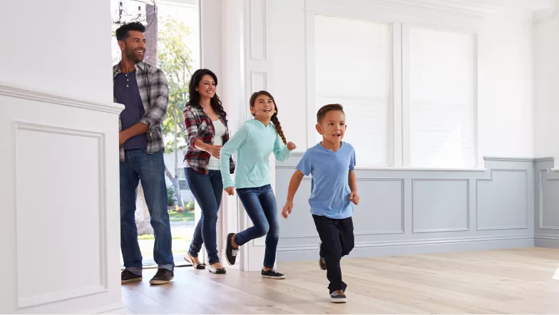 A happy family of four running into their home.